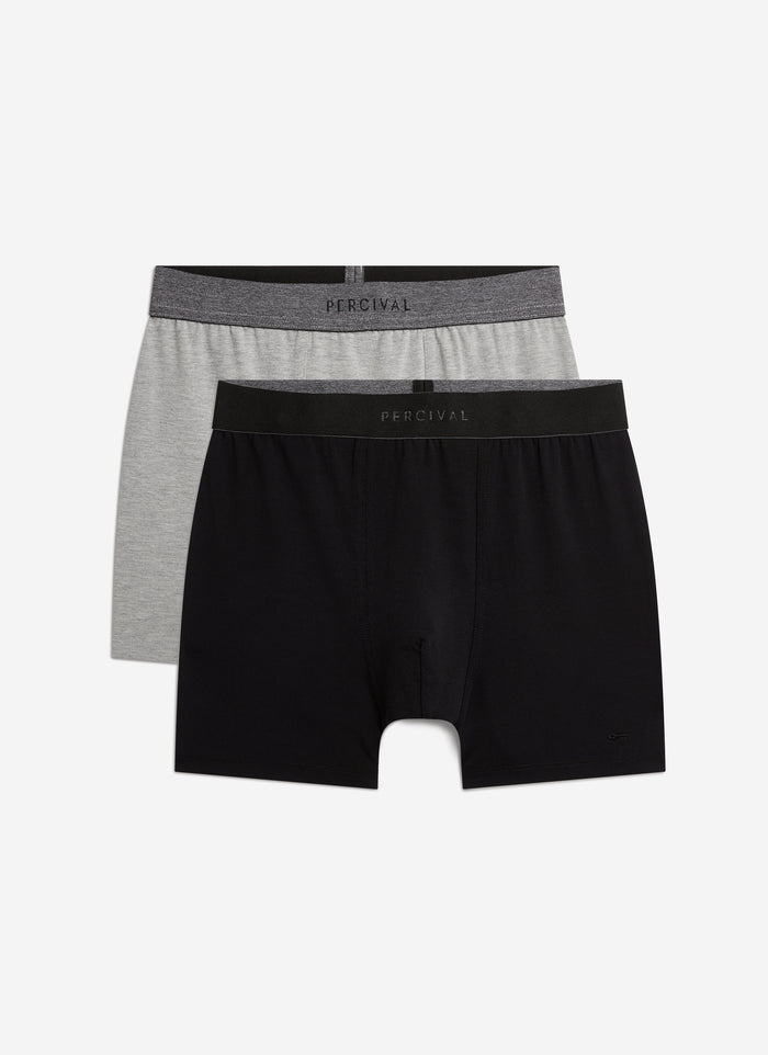 A pair of black and a pair of grey cotton stretch trunks from Percival, shown flat against a white background.
