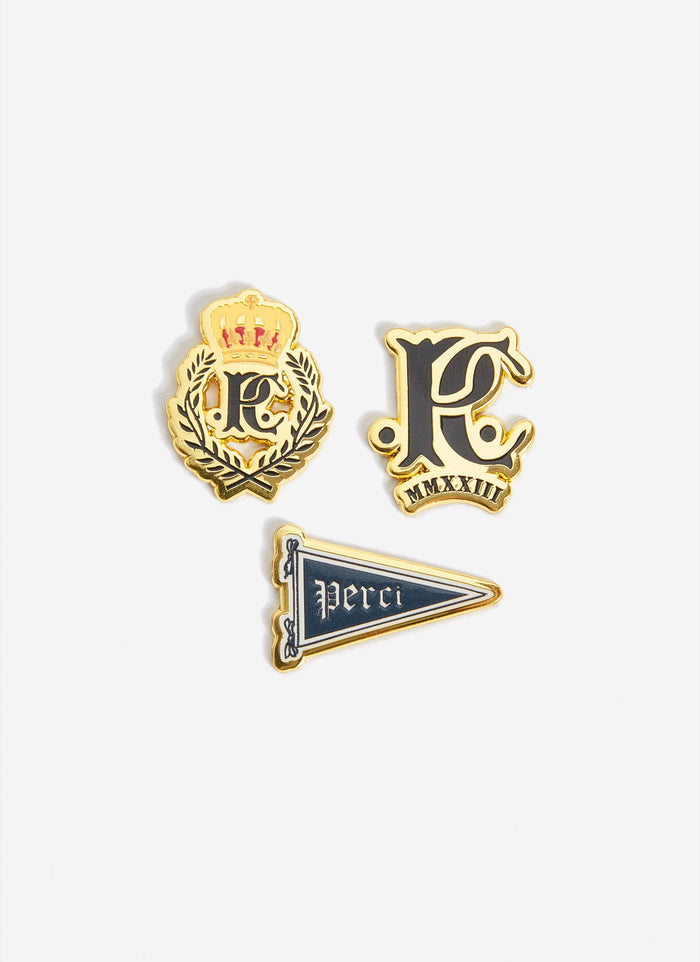 The three gold and black enamel pin badges from the Champion x Percival collaboration, shot against a plain white background.