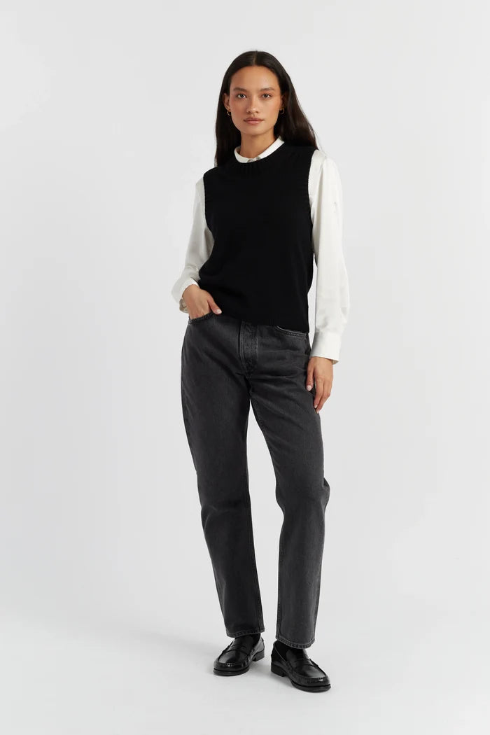 Person wearing a black sleeveless top, white long-sleeve shirt, gray pants, and black shoes on a white background