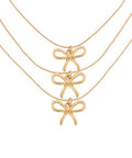 Gold bow pendant necklace with delicate layered chains, photographed for The Pink Doxie Boutique.