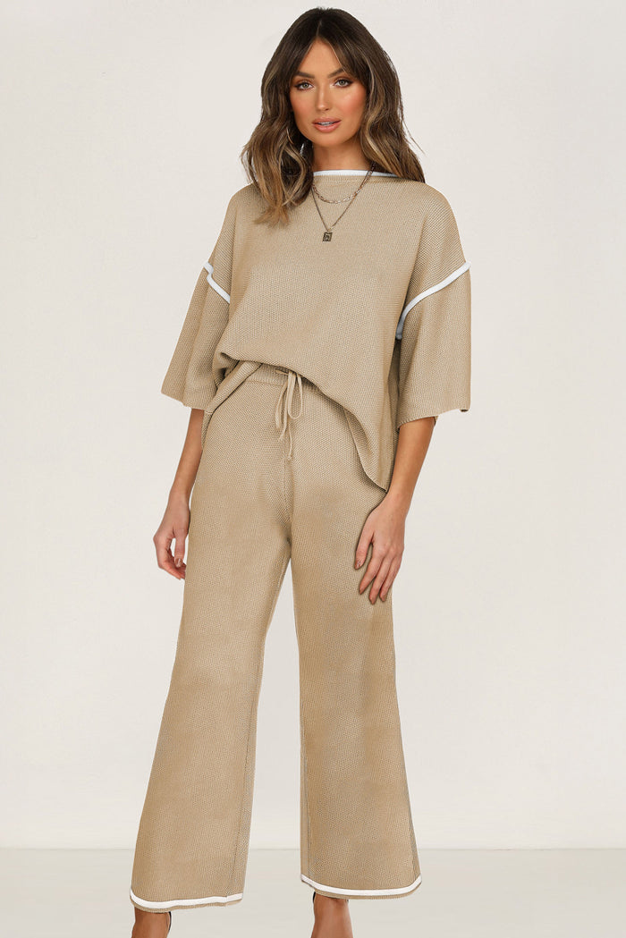 Woman wearing a camel knit sweater set with contrast trim, featuring a half sleeve top and drawstring pants.