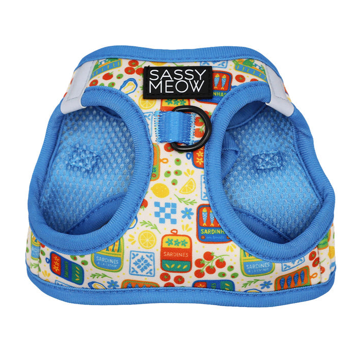 The Sassy Woof Cat Bundle - Portofino is a colorful adjustable harness with blue trim and mesh lining, featuring sardine cans, fruit, and shapes. It has a “Sassy Meow” label and a metal ring for leash attachment on the back.