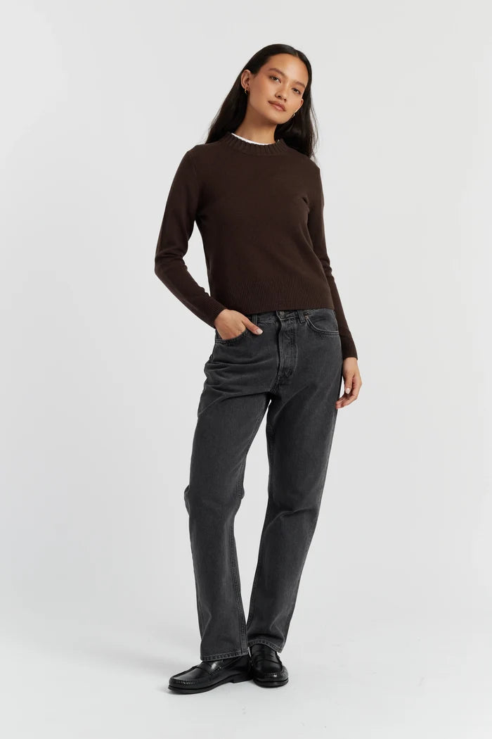 Person wearing a brown long-sleeve shirt and black jeans on a white background