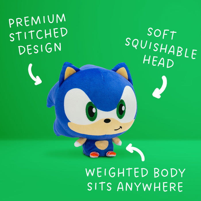 Sonic the Hedgehog Cloudhead - he has a big head, tiny body, and is smirking. Around him are the words "premium stitched design" "soft squishable head" and "weighted body sits anywhere" with arrows pointing to the plushie.