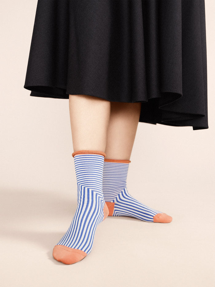 Crew socks in cornflower blue with orange toe and heel, worn with striped shafts