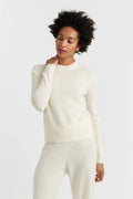 Woman wearing a white sweater and pants on a light gray background