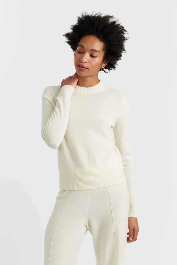 Woman wearing a white sweater and pants on a light gray background