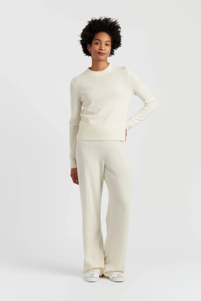 Person wearing a white sweater and pants on a light gray background