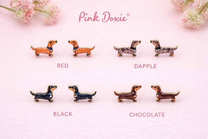 Four pairs of dachshund post earrings displayed on kraft cards labeled Red, Dapple, Black, and Chocolate, featuring enamel dachshund silhouettes from The Pink Doxie Boutique.