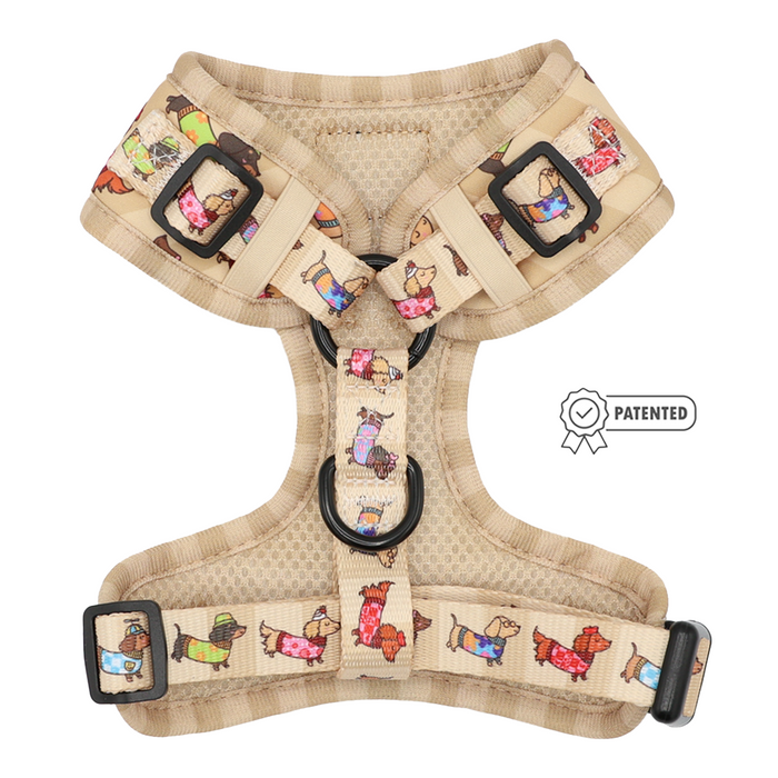 The Sassy Woof Dog Adjustable Harness - Sunbean features a beige base adorned with vibrant cartoon dog illustrations, complemented by black buckles and adjustable straps. This no pull harness is designed for optimal comfort and control during walks. A Patented badge appears to the right of the harness.