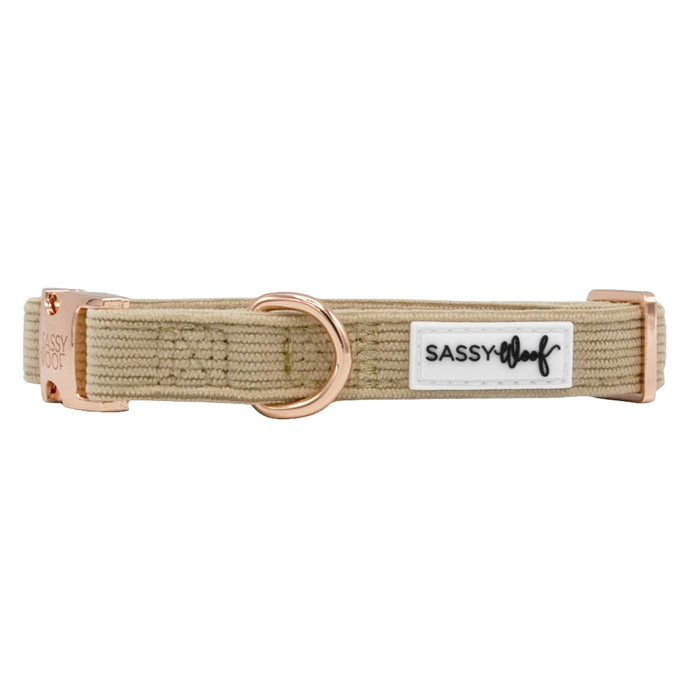 The Sassy Woof Dog Collar - Best Pup is a beige corduroy adjustable collar with rose gold hardware, a D-ring, and a white "SASSY WOOF" patch label—offering comfort and style for your pup.