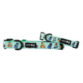 Two light blue Sassy Woof "Chillin with my Gnomies" dog collars featuring garden-themed illustrations—gloves, gnomes, watering cans—a black brand logo tag, and secure leash attachment on each.