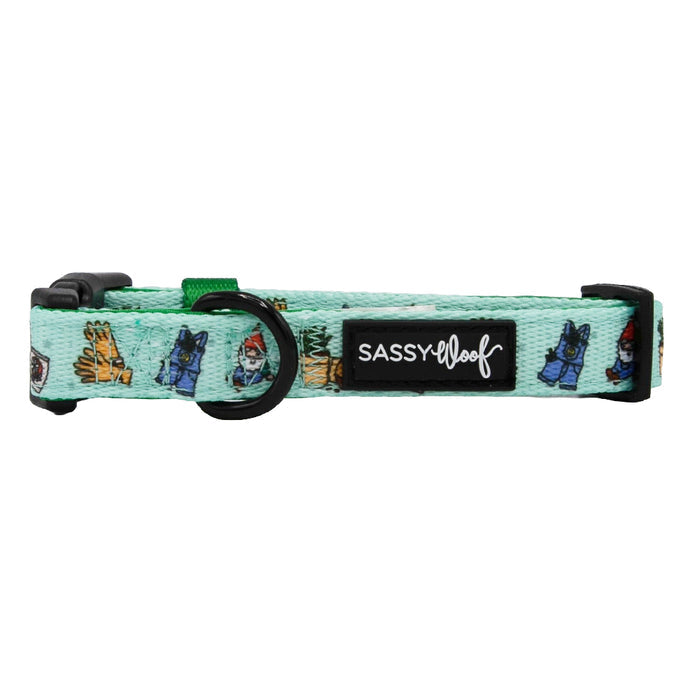 The Sassy Woof Dog Collar - Chillin with my Gnomies is light green neoprene, features garden gnome and glove illustrations, a black plastic buckle, adjustable fit, sturdy leash attachment with metal D-ring, and Sassy Woof label.