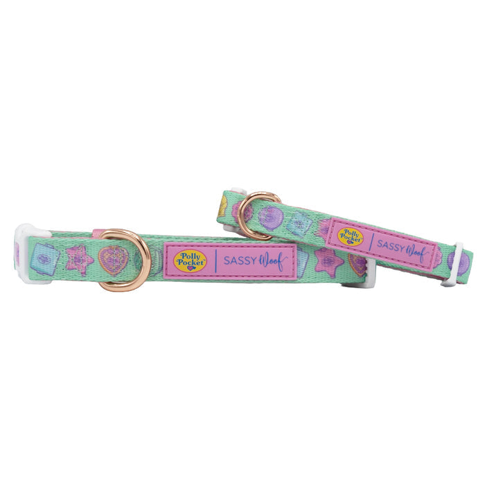 Two pastel green Dog Collar - Polly Pocket™ by Sassy Woof with gold hardware, colorful Polly Pocket-themed designs, playful heart and star patterns, plus pink labels reading "Polly Pocket" and "Sassy Woof." Made of neoprene.