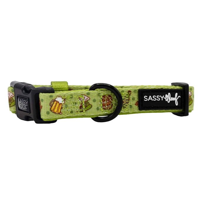 The Sassy Woof Dog Collar - Wurst Behavior is a green neoprene collar with a black buckle and ring, an adjustable fit, playful beer mugs, pretzels, sausages print, and features the SASSY Woof label.