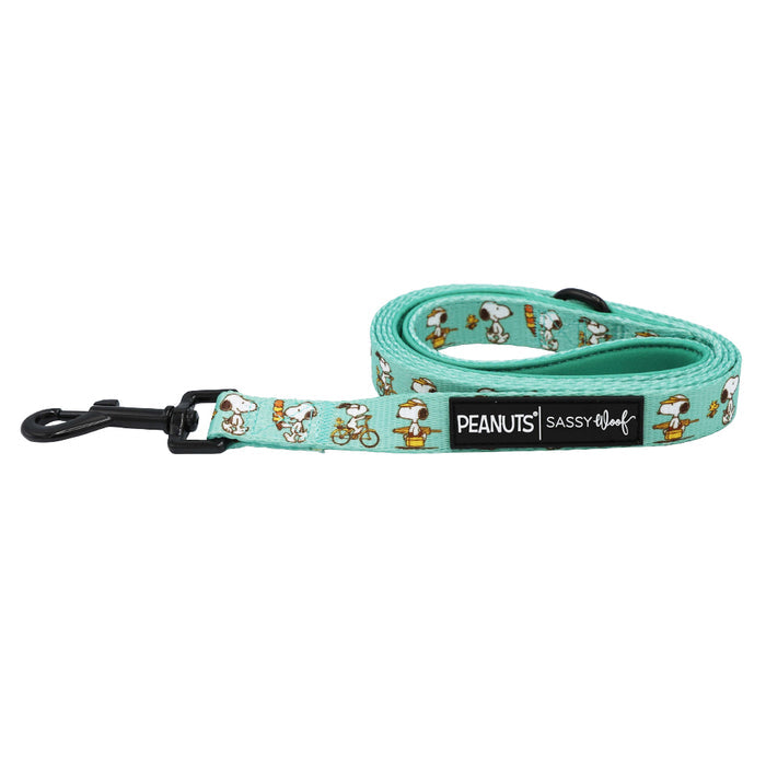 The Sassy Woof Dog Leash - Peanuts™ Road Tripping features mint green neoprene, playful Snoopy patterns, a black clasp, and PEANUTS branding—perfect for fun walks with your dog.