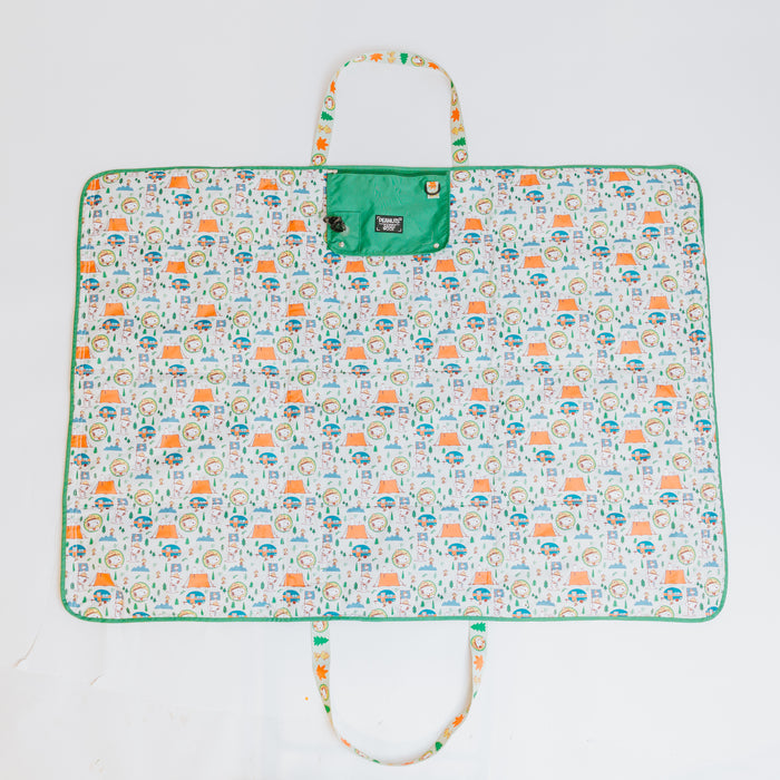 The Sassy Woof Dog Picnic Blanket - Peanuts™ Beagle Scouts features green trim, handles, a playful beagle pattern, and a green snap-flap closure. Laid flat on a white background, it’s perfect outdoor pet gear for your next adventure.