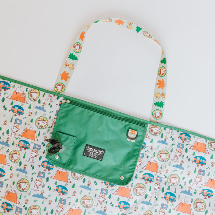 The Sassy Woof Dog Picnic Blanket - Peanuts™ Beagle Scouts features cartoon characters camping among trees and tents, a green pocket labeled "Peanuts," and a handle. Perfect as outdoor pet gear for picnics and adventures.