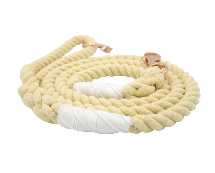 The Sassy Woof Dog Rope Leash - Dandelion is a coiled, thick, beige cotton leash with white accents and a rose gold clasp, shown against a white background.