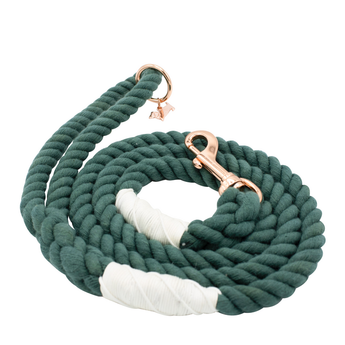 The Sassy Woof Dog Rope Leash - Emerald is a forest green cotton rope leash with white accents, finished with a rose gold clasp and a small bone charm by the handle.
