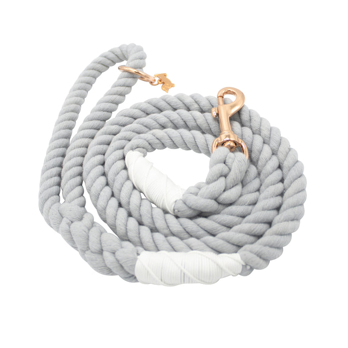 The Sassy Woof Dog Rope Leash - Serenity is a coiled light gray rope leash with white thread accents and durable rose gold hardware, including a stylish metal clasp.