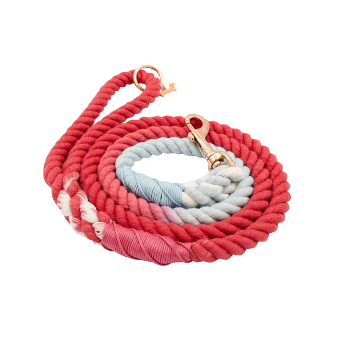 The Sassy Woof Dog Rope Leash - Watermelon Sugar, hand-crafted in red and light blue ombre with a brass clasp and wrapped ends, is coiled on a white background.