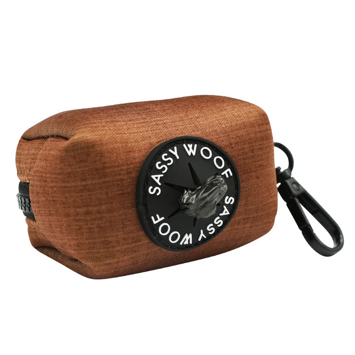 The Sassy Woof Dog Waste Bag Holder - Teddy is a brown neoprene dispenser with a black clip and a SASSY WOOF patch around the opening, stylishly holding waste bags for easy access.