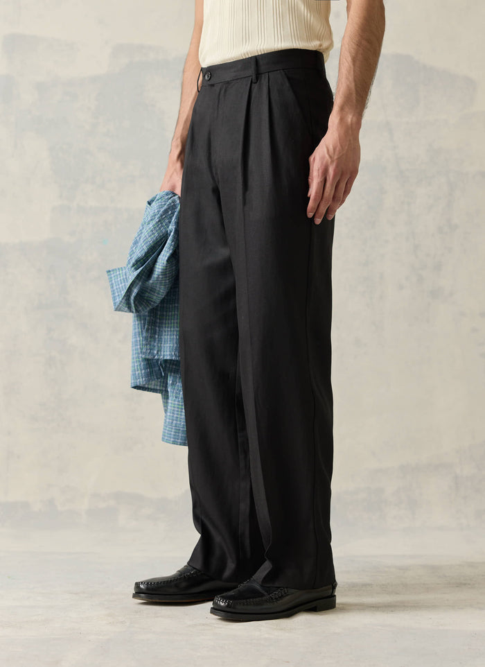 Black double pleated trousers by Percival in a fluid lyocell blend, styled on a model with classic black loafers.