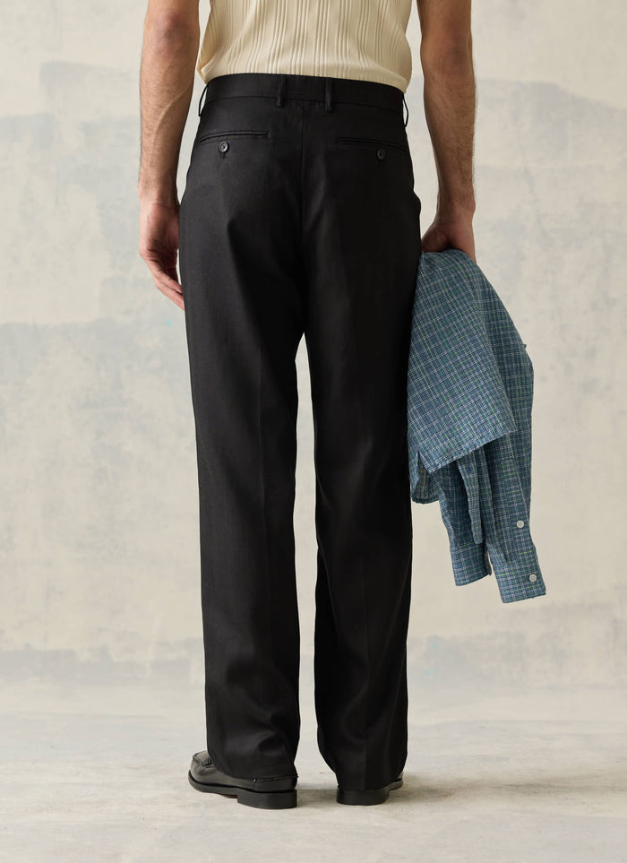 Rear view of Percival black double pleated lyocell trousers, featuring the tailored drape and buttoned back pockets.