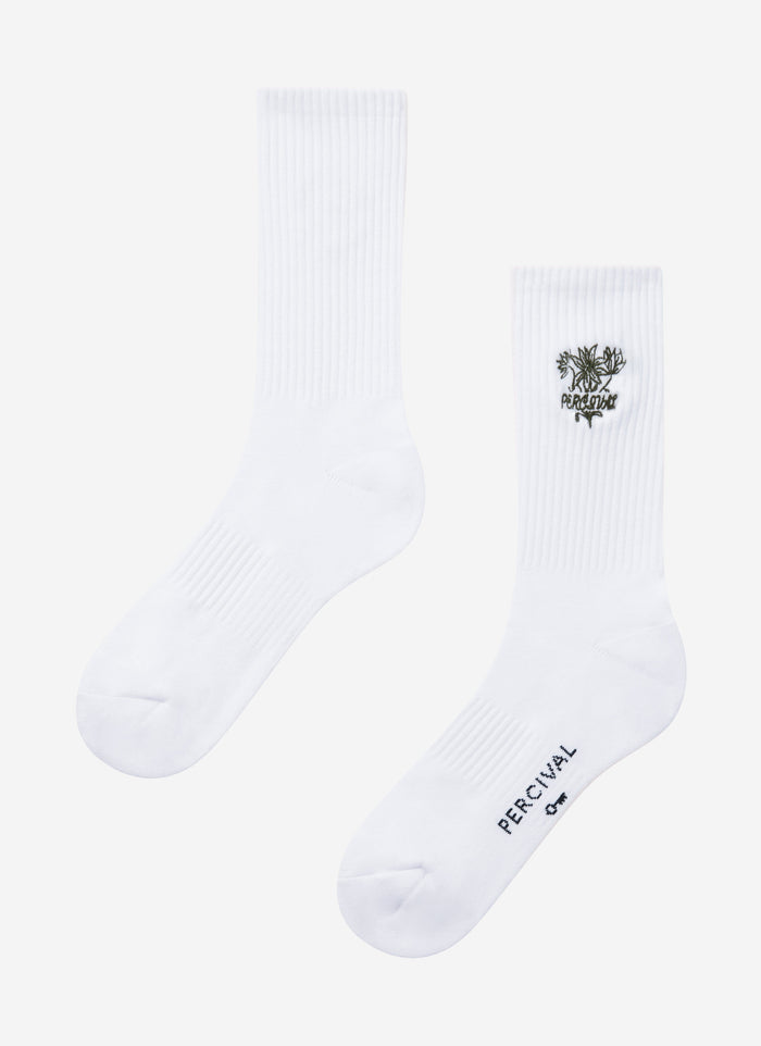 The white Floral Embroidered Socks from Percival, showing the detailed ankle embroidery and branding on the sole.