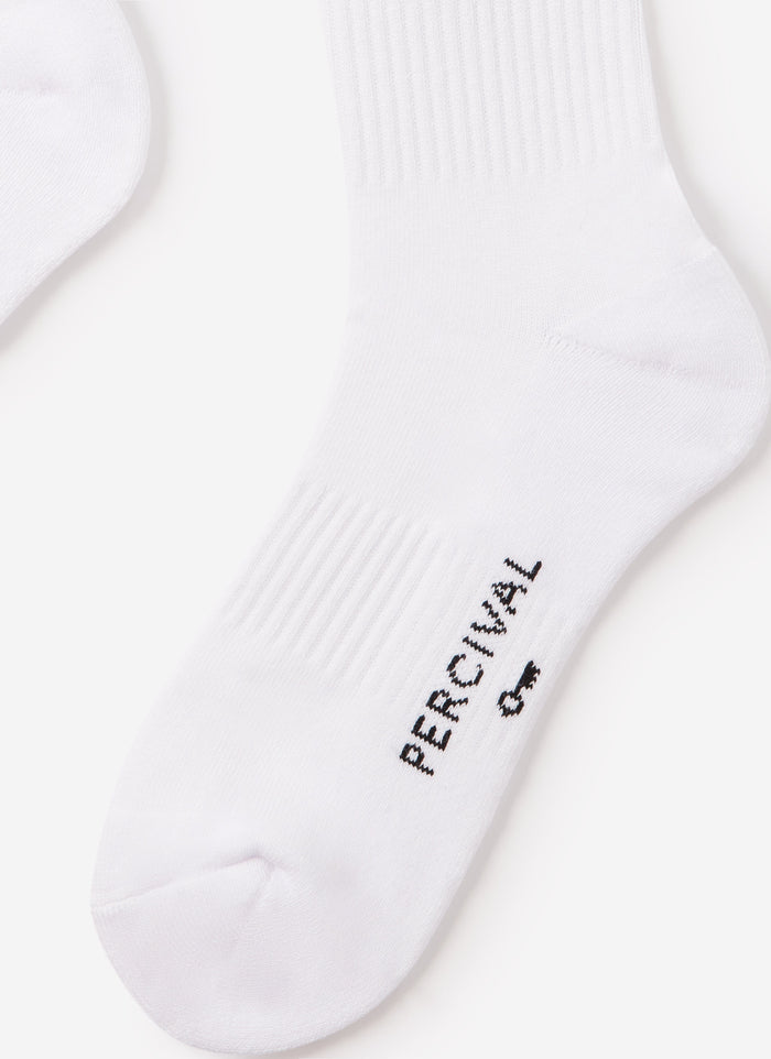 A pair of white Percival crew socks with delicate floral embroidery on the ankle, displayed on a neutral background.