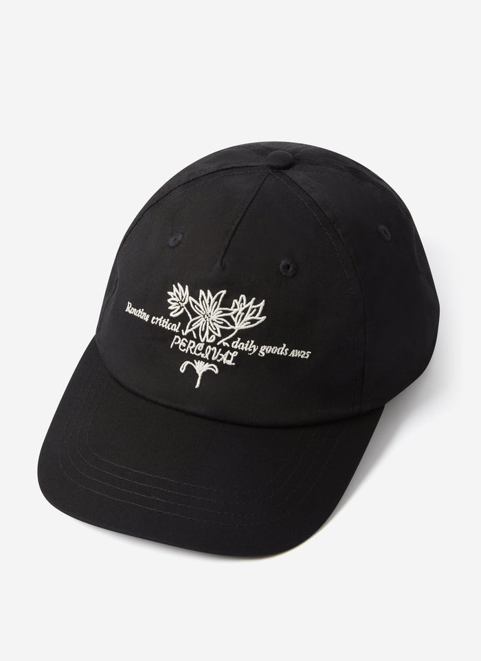 The Percival Floral Embroidered Trucker Cap in black cotton, shown on a plain background with its white floral embroidery.