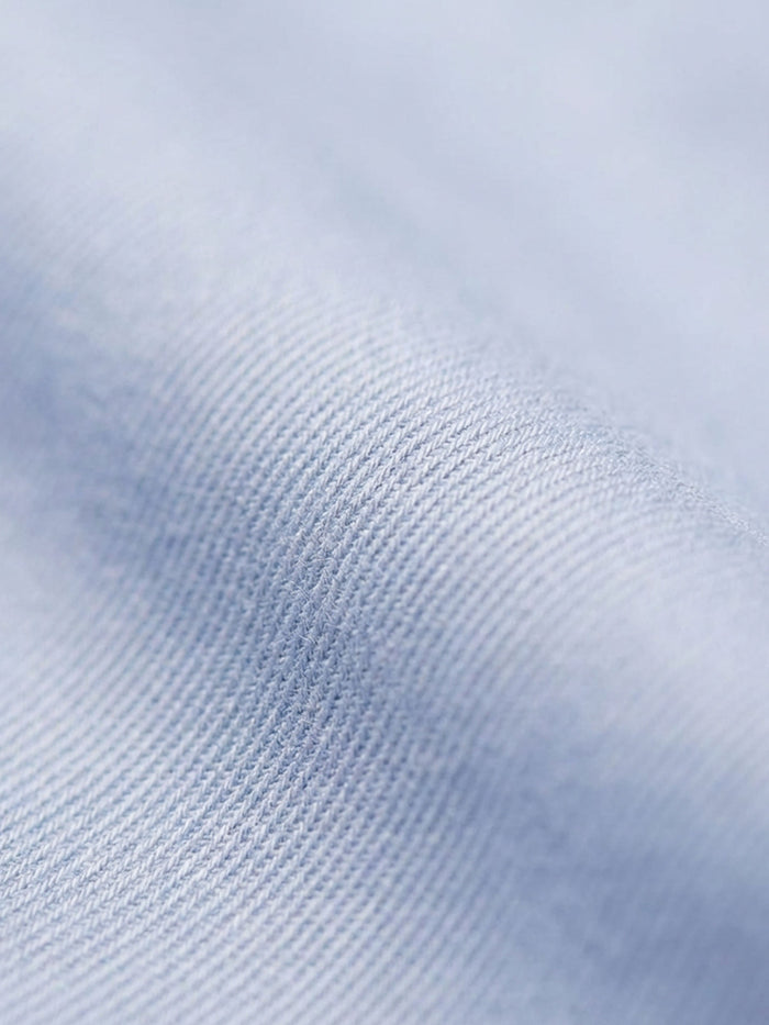 Close-up of light blue men’s shirt fabric showing smooth texture and fine weave