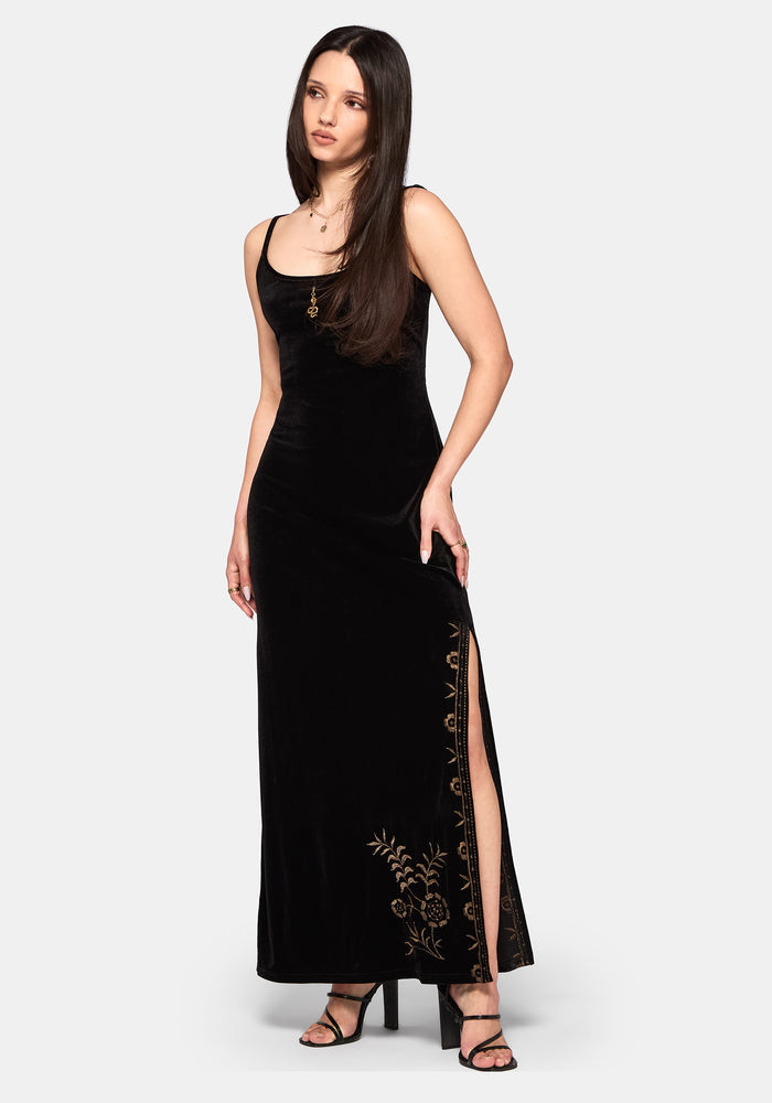 Woman wearing a black dress with floral embroidery on a white background