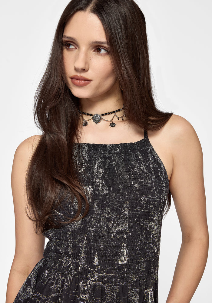 Woman wearing a black printed playsuit with a white background