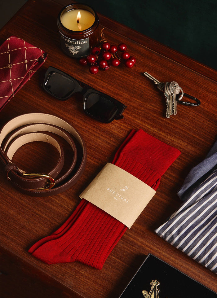 The red ribbed Loafer Dress Socks by Percival, displayed on a wooden table among other classic men's accessories.