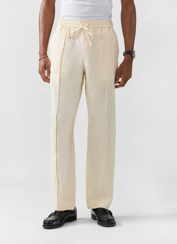 A model wears the cream linen Lorena Wide Leg Trousers from Percival, showing their relaxed fit and drawstring waist.