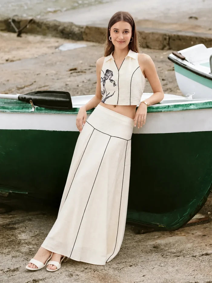 Woman in a stylish outfit standing next to a boat on a beach.