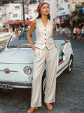 Woman in a striped outfit standing next to a vintage car on a street.