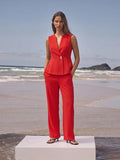 Woman in a red outfit standing on a beach with ocean waves in the background