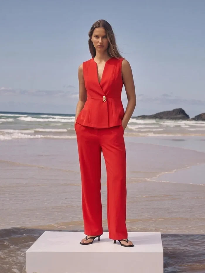 Woman in a red outfit standing on a beach with ocean waves in the background