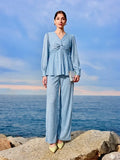 Woman in a light blue outfit standing on rocks with ocean and sky in the background