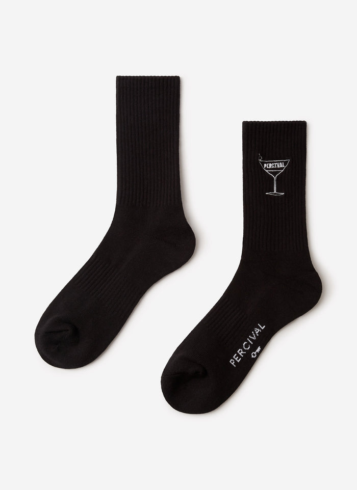 A pair of black Percival Martini Embroidered Socks laid flat, showing the white cocktail glass embroidery and logo detail.