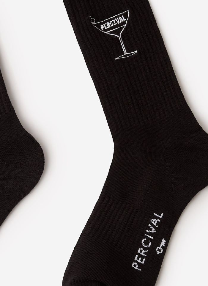 A close-up of the Percival Martini Embroidered Socks in black, showing the signature white martini glass logo embroidery.