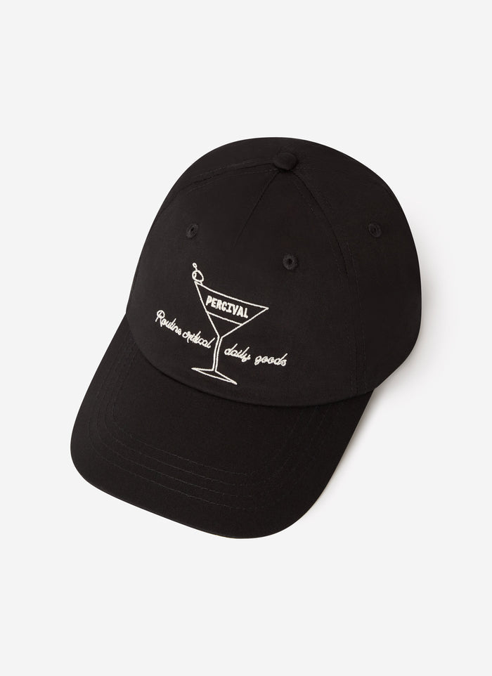 The Percival Martini Trucker Cap in black, featuring white embroidery of a martini glass on the front, on a white background.