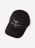 The Percival Martini Trucker Cap in black, featuring white embroidery of a martini glass on the front, on a white background.