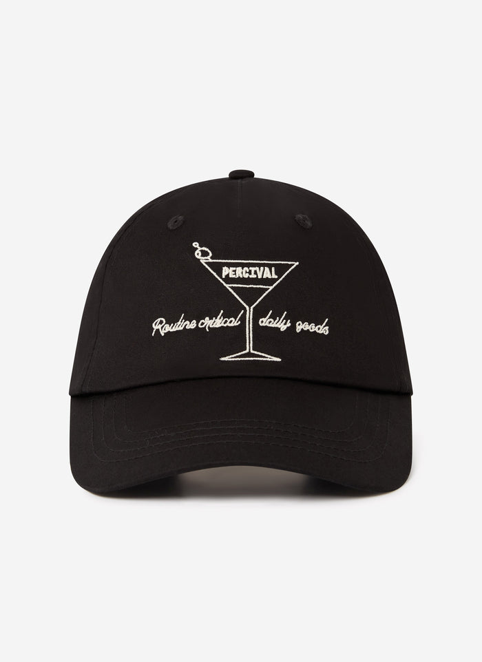 A front view of the Percival Martini Trucker Cap in black, featuring its signature white martini glass embroidery.