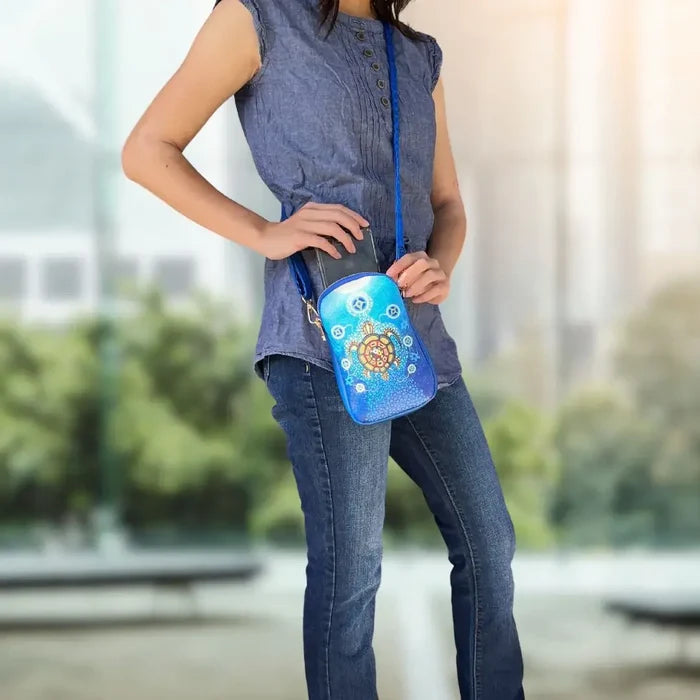 A person wearing the Medicine Turtle Phone Bag, showcasing its vibrant design and convenient size.