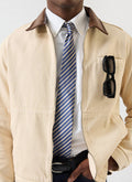 A close-up shot of a model wearing the Percival Micro Stripe Silk Tie with a crisp white shirt and a beige zip jacket.