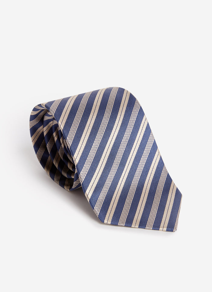 A studio shot of the Percival Micro Stripe Silk Tie in navy and beige, coiled on a white background to show its texture.